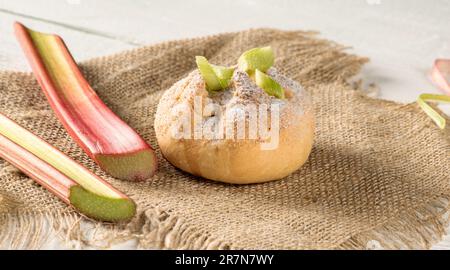 Rhabarberbrötchen und Rhabarberstiele auf einer Serviette auf einem Holztisch Stockfoto