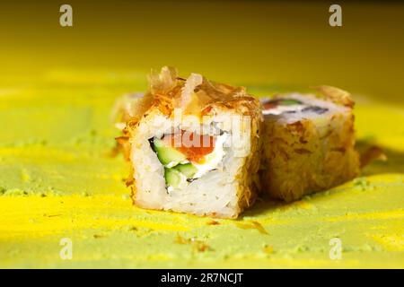 japanische Brötchen mit Fisch, Gurke und Käse auf gelbem Hintergrund Stockfoto