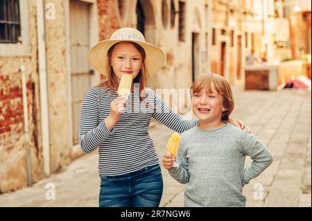 Zwei lustige Kinder, die durch die alten italienischen Straßen spazieren, Familie tavel mit Kindern. Kinder essen Eis Stockfoto