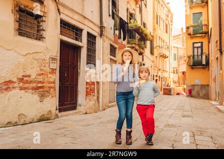 Zwei lustige Kinder, die durch die alten italienischen Straßen spazieren, Familie tavel mit Kindern. Kinder essen Eis Stockfoto