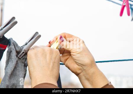 Die Wäschefrau hängt nach dem Waschen zu Hause ein sauberes, nasses Tuch auf den Wäschetrockner. Hausarbeit und Haushalt Stockfoto