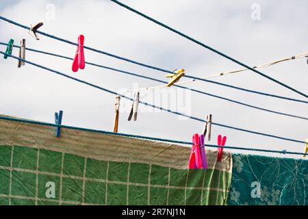 An der Wäscheleine hängt ein Wäschekorb. Ein Seil mit sauberer Bettwäsche und Kleidung draußen am Tag der Wäsche. Vor dem Hintergrund der grünen Natur Stockfoto