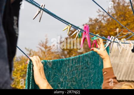 Die Wäschefrau hängt nach dem Waschen zu Hause ein sauberes, nasses Tuch auf den Wäschetrockner. Hausarbeit und Haushalt Stockfoto