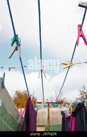 An der Wäscheleine hängt ein Wäschekorb. Ein Seil mit sauberer Bettwäsche und Kleidung draußen am Tag der Wäsche. Vor dem Hintergrund der grünen Natur Stockfoto