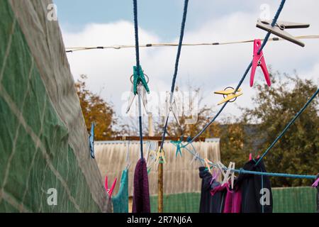 An der Wäscheleine hängt ein Wäschekorb. Ein Seil mit sauberer Bettwäsche und Kleidung draußen am Tag der Wäsche. Vor dem Hintergrund der grünen Natur Stockfoto