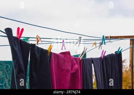 An der Wäscheleine hängt ein Wäschekorb. Ein Seil mit sauberer Bettwäsche und Kleidung draußen am Tag der Wäsche. Vor dem Hintergrund der grünen Natur Stockfoto