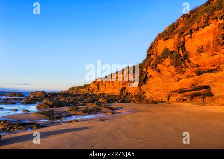 Malerische Sandsteinklippen am Strand der Caves bei Sonnenaufgang und weichem Sonnenlicht an der australischen Pazifikküste. Stockfoto