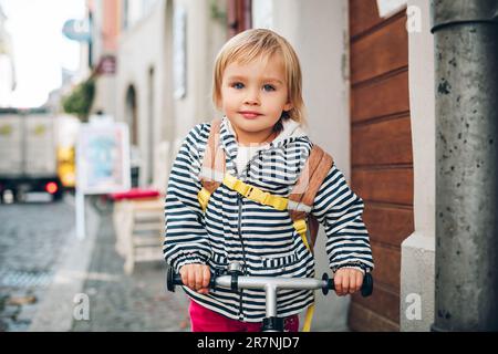 Außenporträt eines süßen kleinen Mädchens, das Fahrrad fährt, einen Rucksack trägt Stockfoto