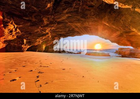 Heller Sonnenaufgang über dem Pazifischen Ozean aus dem Inneren der Sea Cave in Caves Beach. Stockfoto