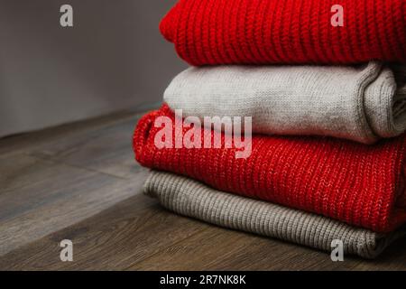 Muster bunter Strickpullover Nahaufnahme. Handgefertigte Merinowolle. Ein Stapel gefalteter Kleidung mit Blumen Stockfoto