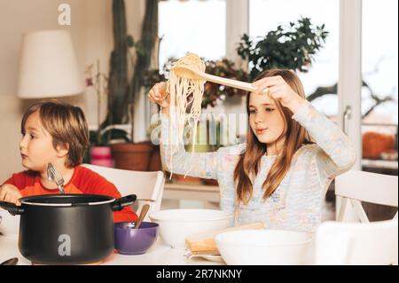 Zwei Kinder essen zu Hause Spaghetti Stockfoto