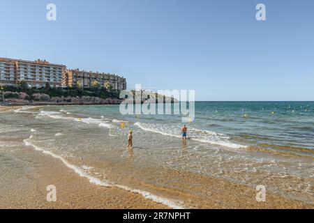 Eine Frau und ein Mann baden am Ufer von Platja Capellans in der Stadt Salou Provinz Tarragona, Katalonien, Spanien, Europa Stockfoto