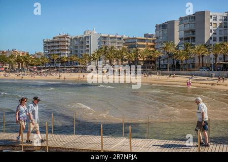 Ein Paar und ein Mann gehen in die entgegengesetzte Richtung auf der hölzernen Fußgängerbrücke am camino de ronda der Salou Route, Tarragona, Katalonien, Spanien. Stockfoto