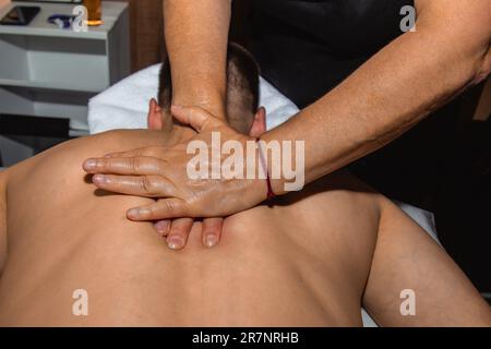 Weibliche Masseurin macht therapeutische Rückenmassage mit Händen an männlichen Sportler. Eine Frau massiert einen Mann. Stockfoto