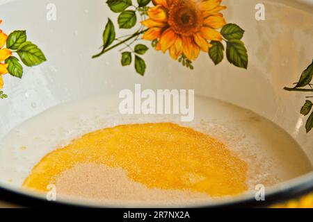 Öl, das in eine Metallschüssel in die Milch gegossen wird. Teigzubereitung. Rezeptpuffer-Gebäck. Backzutaten, Nahaufnahme, Draufsicht. Stockfoto