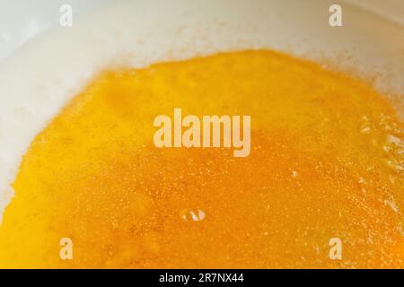 Öl, das in eine Metallschüssel in die Milch gegossen wird. Teigzubereitung. Rezeptpuffer-Gebäck. Backzutaten, Nahaufnahme, Draufsicht. Stockfoto