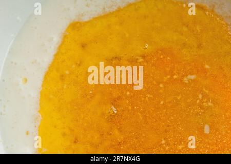 Öl, das in eine Metallschüssel in die Milch gegossen wird. Teigzubereitung. Rezeptpuffer-Gebäck. Backzutaten, Nahaufnahme, Draufsicht. Stockfoto