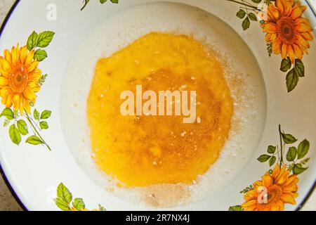 Öl, das in eine Metallschüssel in die Milch gegossen wird. Teigzubereitung. Rezeptpuffer-Gebäck. Backzutaten, Nahaufnahme, Draufsicht. Stockfoto