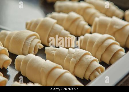 Auf dem Backblech liegt rohes, gemischtes Blätterteiggebäck in Form eines Bagels mit Beeren. Backform Stockfoto