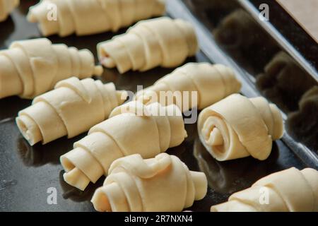 Auf dem Backblech liegt rohes, gemischtes Blätterteiggebäck in Form eines Bagels mit Beeren. Backform Stockfoto