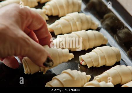 Auf dem Backblech liegt rohes, gemischtes Blätterteiggebäck in Form eines Bagels mit Beeren. Backform Stockfoto