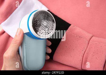 Frau, die den Rasierer in der Nähe des Pullis mit Fusseln hält, Nahaufnahme Stockfoto