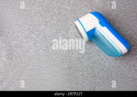 Moderner Rasierer auf hellgrauem Tuch mit Fusseln, Draufsicht. Platz für Text Stockfoto