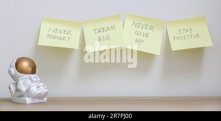 Inspirationskonzept, vier gelbe Haftnotizen mit Motivationsbotschaften an der Wand, damit Sie nie vergessen, große Träume zu träumen, niemals aufzugeben und in Position zu bleiben Stockfoto