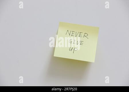 Gelbe Haftnotiz an der Wand mit motivierender und inspirierender Botschaft, nie aufzugeben, Erinnerung, im Leben weiterzumachen und für deinen Traum zu arbeiten Stockfoto