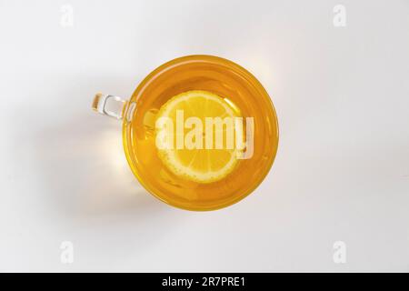 Transparente Tasse Tee mit Zitrone auf weißem Hintergrund von oben nach unten Stockfoto