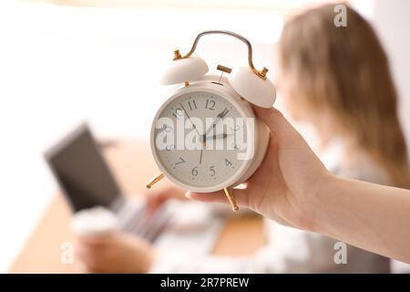 Frau mit Wecker im Büro, Nahaufnahme Stockfoto