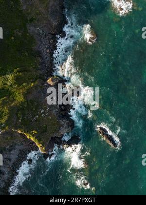Luftaufnahme der zerklüfteten Küste von Cornwall in der Nähe des Dorfes Kuggar mit dem klaren Ozean auf den Felsen. Stockfoto