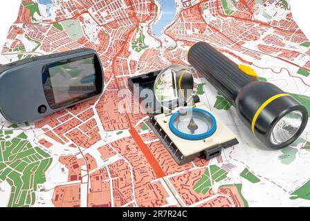 Auf einer Topokarte befinden sich ein tragbares GPS, eine Taschenlampe und eine Kompasseinheit Stockfoto