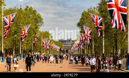 London, 29. Mai 2023: Fußgänger laufen entlang der Mall, Union Jack Flags auf beiden Seiten entlang der Straße, Admiralty Arch im Hintergrund. Stockfoto