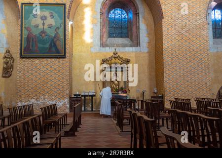 Moissac, Frankreich - 2. November 2022: Eine nicht wiedererkennbare alte Nonne, von hinten gesehen, reinigt das Innere der Abtei Saint-Pierre Stockfoto