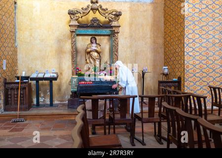 Moissac, Frankreich - 2. November 2022: Eine kaum wiedererkennbare alte Nonne, von hinten gesehen, putzt in der Abtei Saint-Pierre Stockfoto