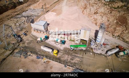 Luftaufnahme von Betonmischwagen und Silos in Zementfabriken. Industriebeton-Chargenanlage aus der Vogelperspektive. Stockfoto