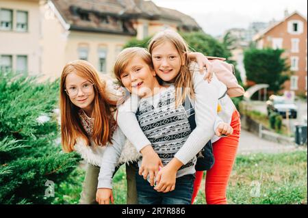 Gruppe von 3 lustigen Kindern mit Rucksäcken, 2 Schulmädchen und ein Vorschulkind, Konzept für die Rückkehr zur Schule Stockfoto