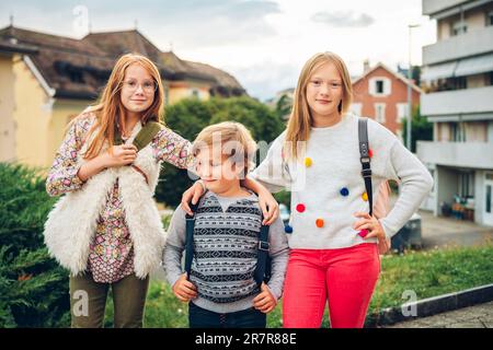 Gruppe von 3 lustigen Kindern mit Rucksäcken, 2 Schulmädchen und ein Vorschulkind, Konzept für die Rückkehr zur Schule Stockfoto