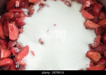 Frische Erdbeeren, mit Zucker bestreut, um Marmelade zu machen. Papierstau verursachen. Rote und reife Erdbeeren mit Zucker bestreut Stockfoto