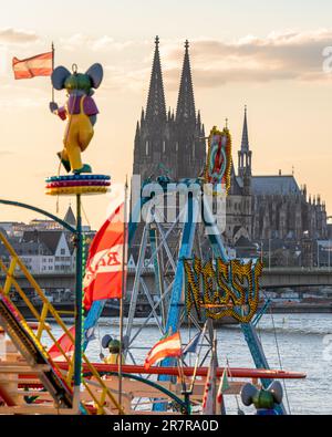 KÖLN, DEUTSCHLAND - 19. APRIL 2023: Skyline der Stadt mit Dom mit Jahrmarkt im Vordergrund bei Sonnenuntergang am 19. April 2023 in Köln Stockfoto