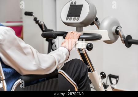 Eine nicht erkennbare ältere Frau macht Pedalübungen vom Rollstuhl im Krankenhaus. Hochwertiges Foto. Stockfoto