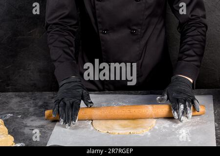 Zubereitung des Teigs. Den Teig mit einem Holzrollstift ausrollen Stockfoto