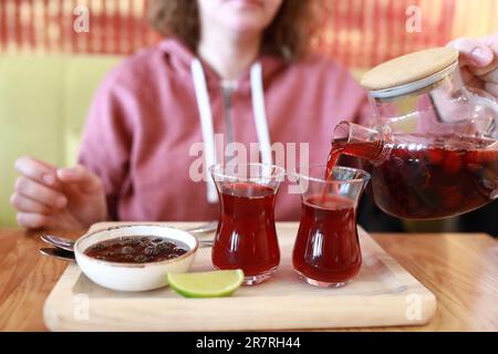 Person, die im Restaurant Obsttee in armuduistische Gläser gießt Stockfoto