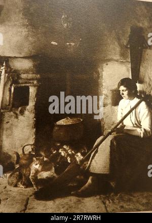 Eine typische einheimische Szene in einem Landhaus in Connemara, Irland 1933, mit einer Frau, die neben dem Feuer mit ihren Katzen sitzt. Stockfoto