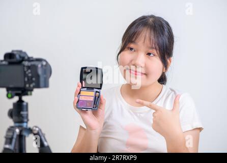Beauty Girl Blogger Konzept, asiatische Frau verwendet Pinsel, um Lidschatten und Rezensionen in Livestreaming zu verwenden. Stockfoto