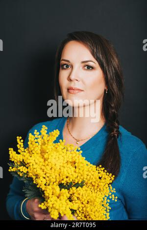 Frühlingsporträt einer schönen Frau mit gelben Mimosablüten Stockfoto