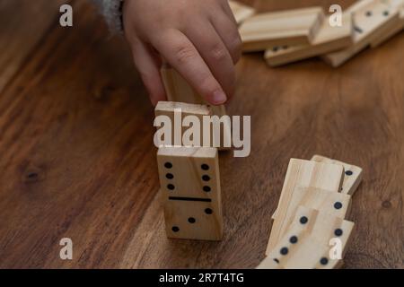 Kinderhände in grauem Pullover spielen Dominosteine mit verschwommenem Fokus Stockfoto