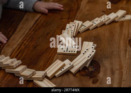 Kinderhände in grauem Pullover spielen Dominosteine mit verschwommenem Fokus Stockfoto