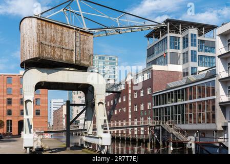 Historischer Hafenkran im Hafen von Harburg. Alte umgebaute Lagerhäuser und neue Bürogebäude im Hafen. Die Stadt und der Bezirk sind es Stockfoto